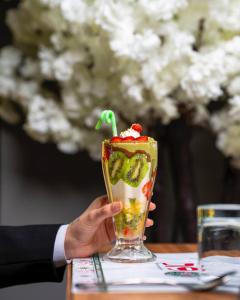 une personne tient un verre avec une boisson dans l'établissement Ward Hotel Basra, à Bassorah
