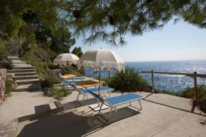 un gruppo di sedie e ombrelloni accanto all'oceano di Villa Santa Maria - Luxury Country House Suites ad Amalfi