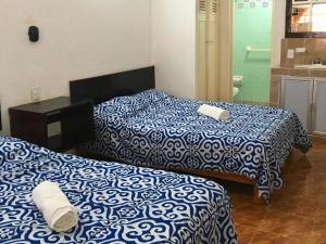 2 camas con sábanas azules y blancas en una habitación en Suite Victoria Acapulco, en Acapulco