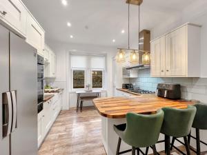 a kitchen with a wooden counter and green chairs at No.3 The Villa in Oban