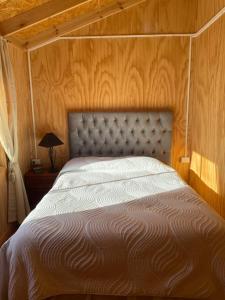 a bedroom with a bed with a wooden wall at Cabañas La Plaza in Bahía Murta