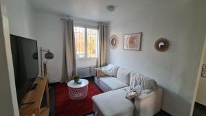 ein Wohnzimmer mit einem Sofa und einem TV in der Unterkunft Cocon douillet de Mélanie in Marignane