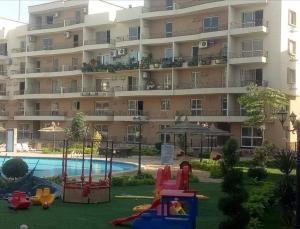 un complejo de apartamentos con parque infantil frente a un edificio en شقة فندقية en Qaryat ash Shamālī