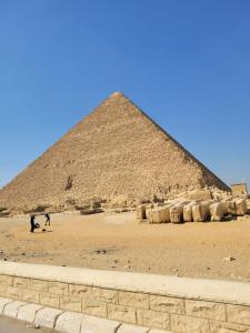 Eine Pyramide mit zwei Menschen, die davor stehen. in der Unterkunft Pyramids Sunrise in Kairo