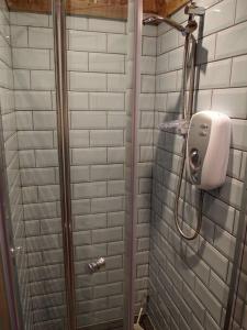 a shower in a bathroom with white tiles at The Snug in Matlock