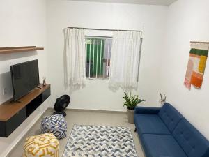 a living room with a blue couch and a television at Aconchego! Sua casa com Piscina em Passos!! in Passos