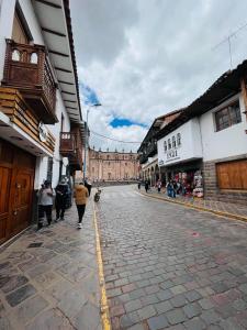 un grupo de personas caminando por una calle con un edificio en Casa Virgen del Carmen, en Cusco