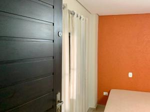 um quarto com uma porta e uma cama com uma parede laranja em Kitnete na praia do centro de Peruibe em Peruíbe