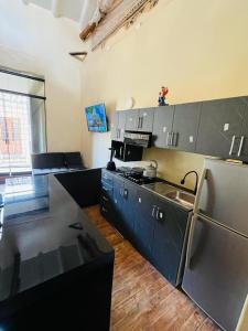 a kitchen with black cabinets and a stainless steel refrigerator at Casa Virgen del Carmen in Cusco