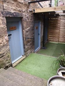 a stone building with two doors and a green yard at The Snug in Matlock