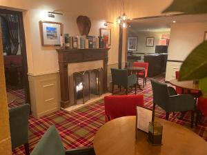 a restaurant with a fireplace and tables and chairs at Glazert Country House Hotel in Lennoxtown