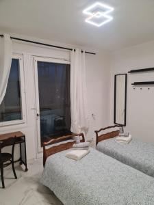 a bedroom with two beds and a desk and a window at ATTICO GENOVA con POSTO AUTO in Genova