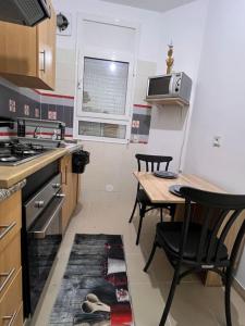 a kitchen with a table and two chairs and a stove at Cosy studio jardin de l’aouina in Tunis