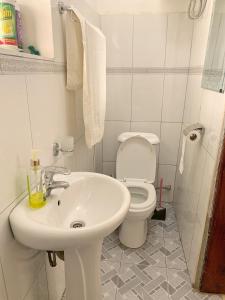 a white bathroom with a toilet and a sink at Missions Cafe Arua - GuestHouse in Arua