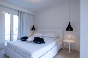 Akrogiali Garden Hotel في ماليا: غرفة نوم بيضاء مع سرير أبيض مع وسائد سوداء