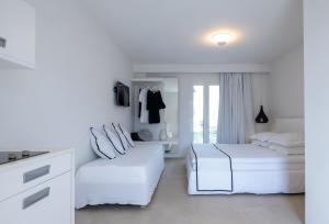 Akrogiali Garden Hotel في ماليا: غرفة نوم بيضاء بسريرين ونافذة