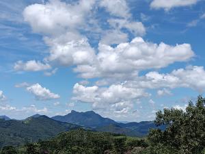 雷森迪德馬烏阿的住宿－Chales Encanto do sol，蓝天,白云覆盖着群山和树木