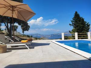een zwembad met een parasol en een stoel ernaast bij Villa Bob in Povlja