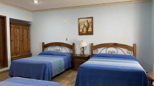 two beds in a room with blue sheets at Posada Regional in Oaxaca City
