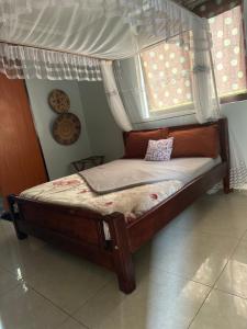 a bed with a canopy in a room with two windows at Missions Cafe Arua - GuestHouse in Arua
