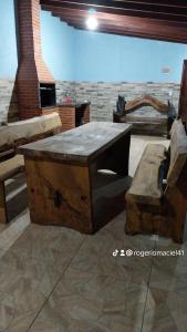 einen Holztisch und eine Bank in einem Zimmer mit Ziegelwand in der Unterkunft Casa de campo maciel in Abel