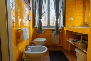 a yellow bathroom with a toilet and a sink at MonferraTO: tutto a due passi in Turin