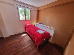 Habitación pequeña con manta roja y ventana en Cabañas Mi Lugar en Las Gaviotas