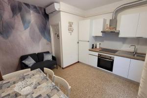 uma cozinha com uma mesa e um sofá num quarto em Appartamento estivo PONENTE - Misano A.(RN) em Misano Adriatico