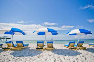eine Gruppe von Stühlen und Sonnenschirmen am Strand in der Unterkunft Best Western Premier - The Tides in Orange Beach