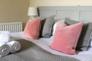a bed with pink and gray pillows on it at Pendle View Apartment in Settle