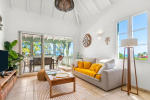 una sala de estar con un sofá y una mesa en Sur la plage de la Baie Orientale - Bel appartement VUE MER 6à7p, en Orient Bay