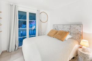 Un dormitorio blanco con una cama y una ventana. en Sur la plage de la Baie Orientale - Bel appartement VUE MER 6à7p, en Orient Bay