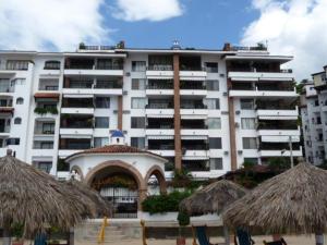 un gran edificio blanco con sombrillas de paja delante en Playa Bonita en Puerto Vallarta