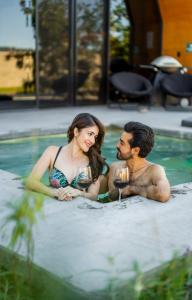 a man and woman sitting in a swimming pool with wine glasses at Akbal Cabañas Boutique in Aguascalientes