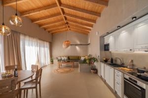 cocina y sala de estar con techo de madera y mesa. en Apeiron Villas en Kefallonia