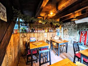um restaurante com mesas e cadeiras de madeira e um bar em Le Noyer em Rougnat
