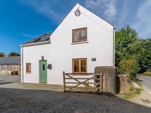 a white house with a green door and a gate at The Gatehouse at Y Gwesty Bach in Jordanston