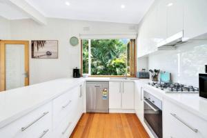 a white kitchen with white cabinets and a window at The perfect Cheltenham escape - 3 bedroom house in Cheltenham