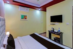 Habitación de hotel con cama y TV en OYO Home Picturesque Stay en Dehradun