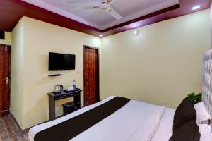 1 dormitorio con 1 cama y TV de pantalla plana en OYO Home Picturesque Stay en Dehradun