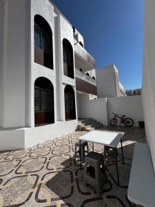 a patio with a table and a bench in front of a building at Viva Hostel Group Muscat in Muscat