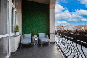 balkon z 2 krzesłami i zieloną ścianą w obiekcie Apartament Silver SAUNA&JACUZZI Poznań Stare Miasto w Poznaniu