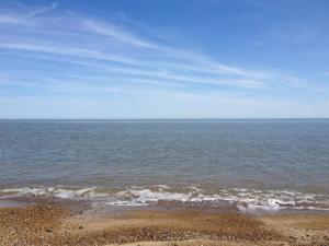 a beach with the ocean and a blue sky at Henrys on the Prom in Great Yarmouth