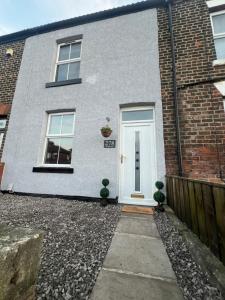 a white door on a brick house with two plants at Cosy home perfect for families and contractors with free parking in Darlington