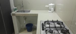 a white kitchen with a stove and a sink at El Encanto ApartaSuite in Barranquilla
