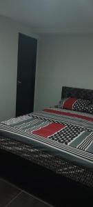 a bedroom with a bed with a black and red comforter at El Encanto ApartaSuite in Barranquilla
