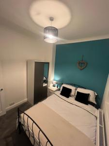 a bedroom with a large bed with a blue wall at Cosy home perfect for families and contractors with free parking in Darlington