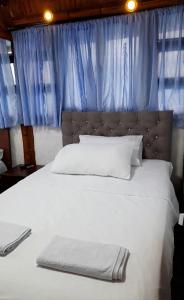 a bedroom with a white bed with a blue curtain at Cabin in the Mountains - Chalet in Ibagué