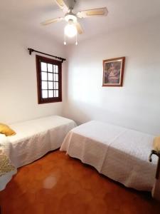 two beds in a room with white walls and a window at Apartamento colibrí in Alaior