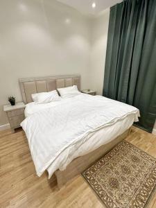 een slaapkamer met een groot wit bed en groene gordijnen bij شقة جميلة بغرفتين نوم ودخول ذاتي 106B in Riyad